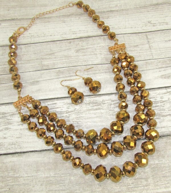 layered necklace and earrings with golden beadwork on a wooden surface