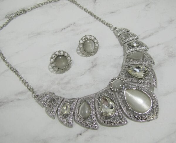 necklace and earrings with pearl and diamond gems on a marble surface