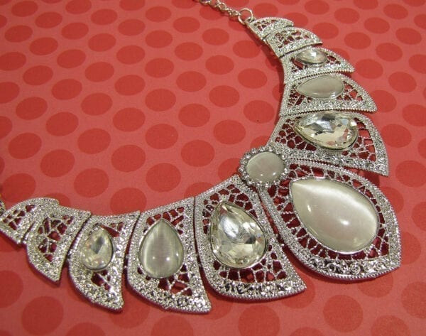 necklace and earrings with pearl and diamond gems on a spotted red surface