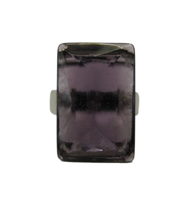 close up view of a ring with square cut violet gem