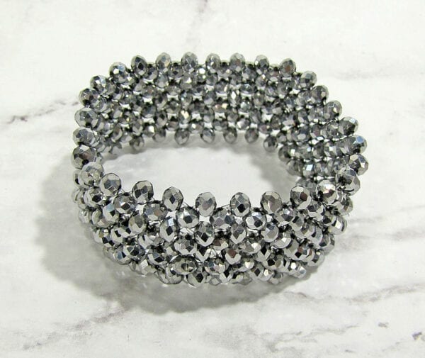 top view of a bracelet with rows of silvery beads on a marble surface
