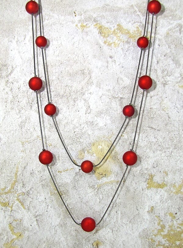 chord necklace with spherical red beads on a concrete surface