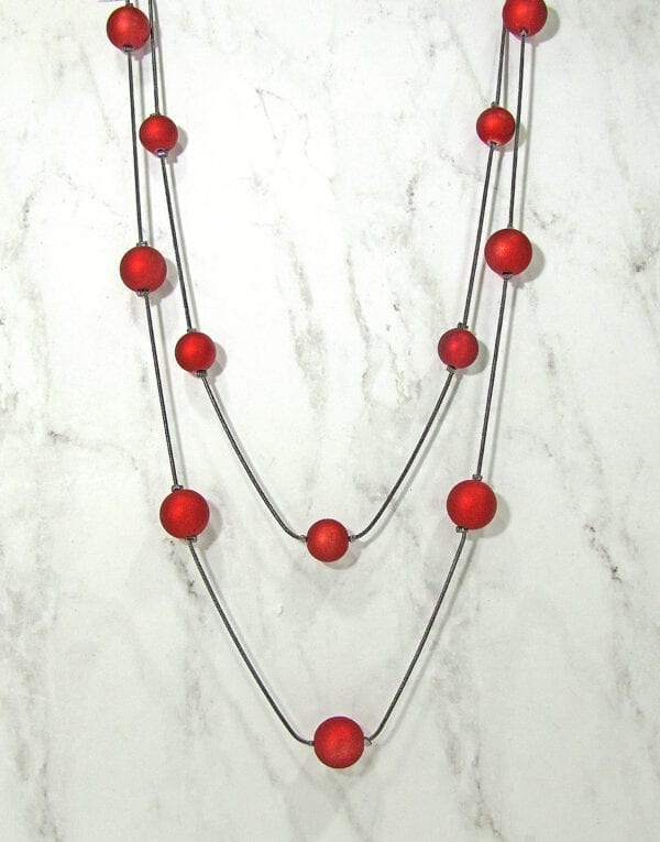chord necklace with spherical red beads on a marble surface