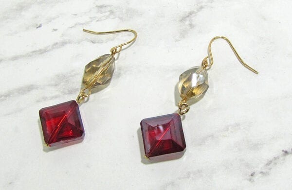 earrings with pale yellow and red gemstones on marble surface