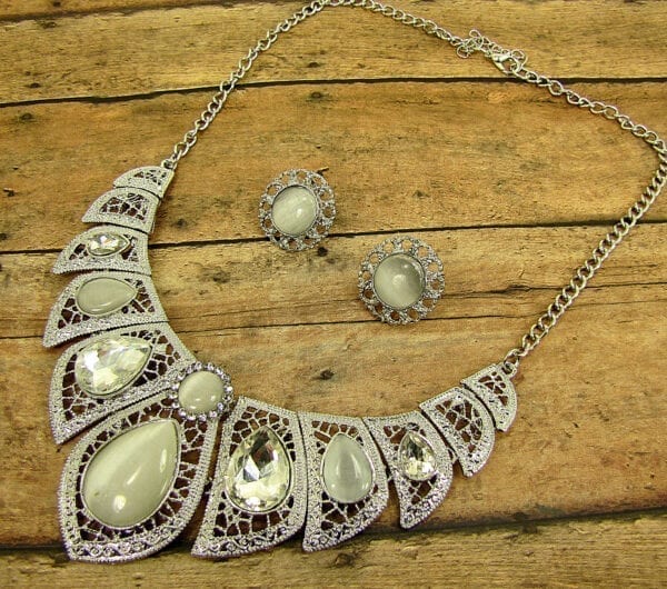 necklace and earrings with pearl and diamond gems on a wooden surface