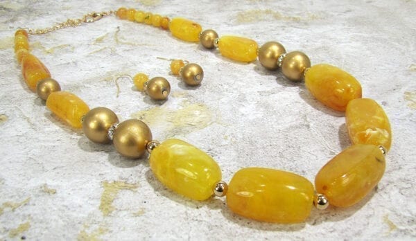 necklaces and earrings with dark yellow beads and gemstones on a concrete surface