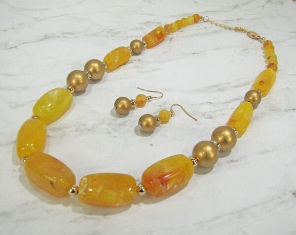 necklaces and earrings with dark yellow beads and stones on a marble surface