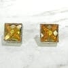 top view of square-cut topaz earrings on marble surface