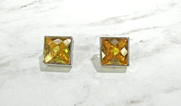 top view of square-cut topaz earrings on marble surface
