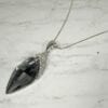 necklace with black gem and metal filigree on a marble surface