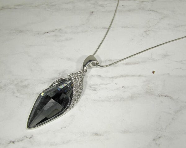 necklace with black gem and metal filigree on a marble surface