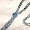 close up of a crystal necklace with large blue gem pendant on a marble surface