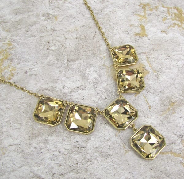 necklace with square cut topaz stones on a concrete surface