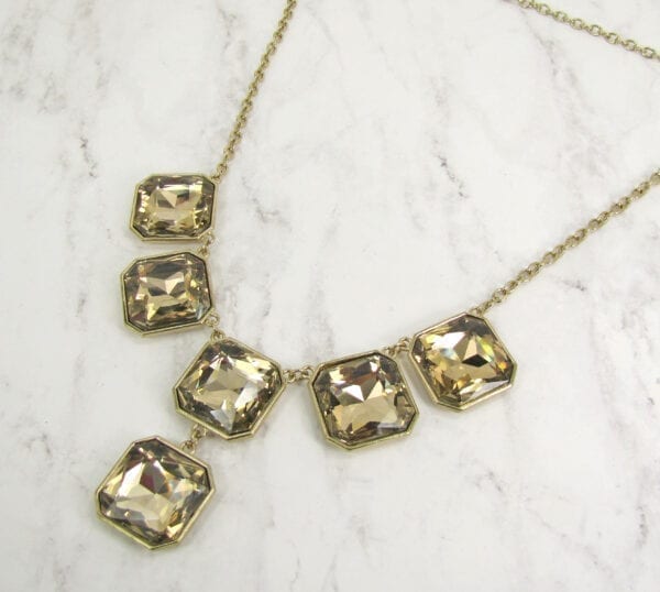 necklace with square cut topaz stones on a marble surface