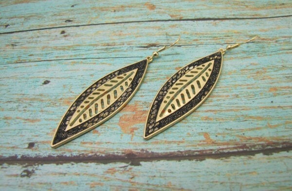 earrings with elongated metal leaf design on a wooden surface