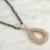 close up of a necklace with teardrop pearl design on marble surface