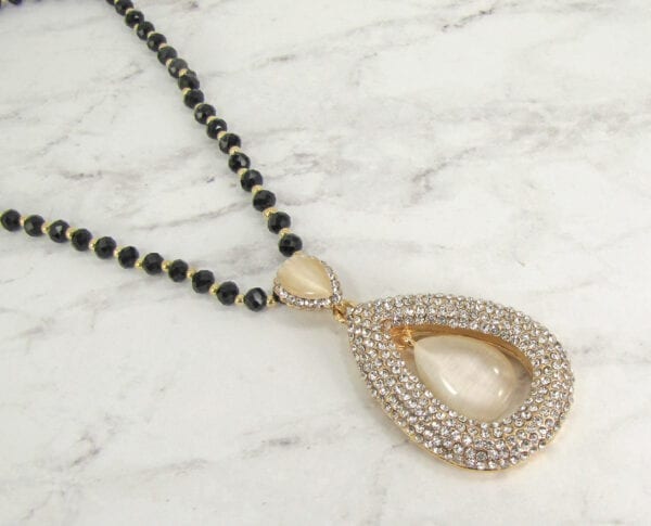 close up of a necklace with teardrop pearl design on marble surface