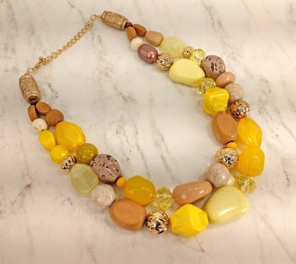 layered necklace with assortment of yellow polished stones and crystals on marble surface