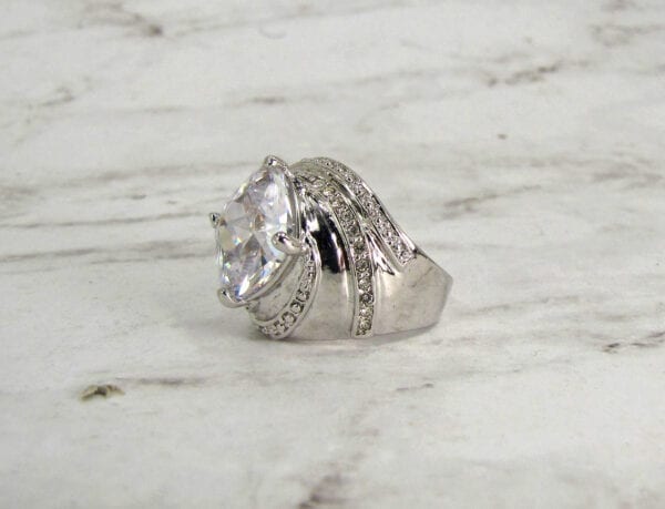 side view of a ring with twisting design and white crystal inset on marble surface