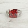 front view of a ring with square-cut garnet gem on a marble surface