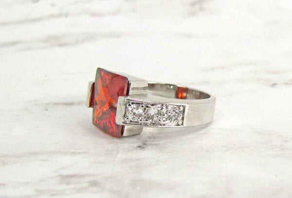 side view of a ring with square-cut garnet gem on a marble surface