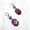 earrings with octagonal deep violet crystals on a marble surface