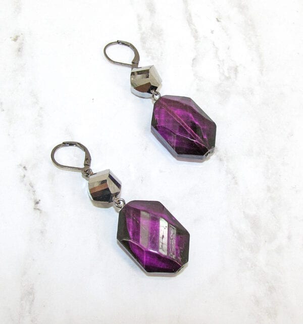 earrings with octagonal deep violet crystals on a marble surface