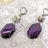 earrings with octagonal deep violet crystals on a concrete surface