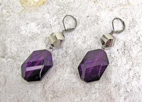 earrings with octagonal deep violet crystals on a concrete surface