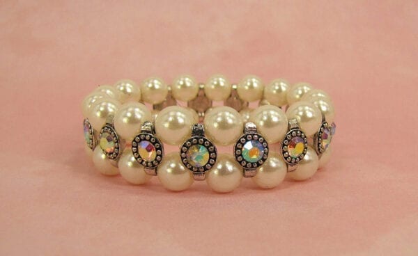 pearl bracelet with rainbow-colored gems on a pink surface