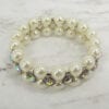 top view of a pearl bracelet with rainbow-colored gems on a marble surface
