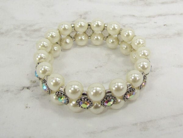 top view of a pearl bracelet with rainbow-colored gems on a marble surface