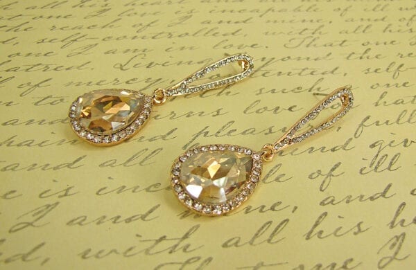 pair of earrings with teardrop amber crystals on a paper surface with scribbles