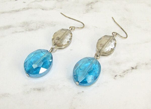 earrings with light brown and sky blue gems on a marble surface