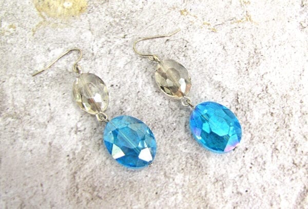 earrings with light brown and sky blue gems on a concrete surface