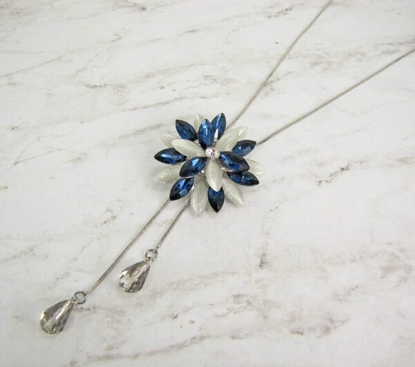 necklace pendant with blue crystals arranged in a starburst on a marble surface