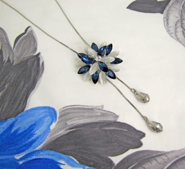 necklace pendant with blue crystals arranged in a starburst on a cloth surface
