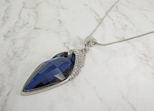 necklace pendant with dark blue gemstone on marble surface