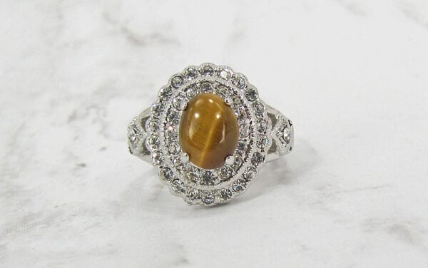 ring with polished oval brown gem on marble surface