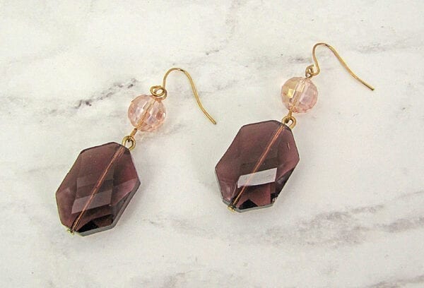 earrings with octagonal violet crystals on a marble surface