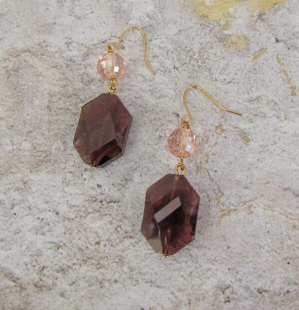 earrings with octagonal violet crystals on a concrete surface