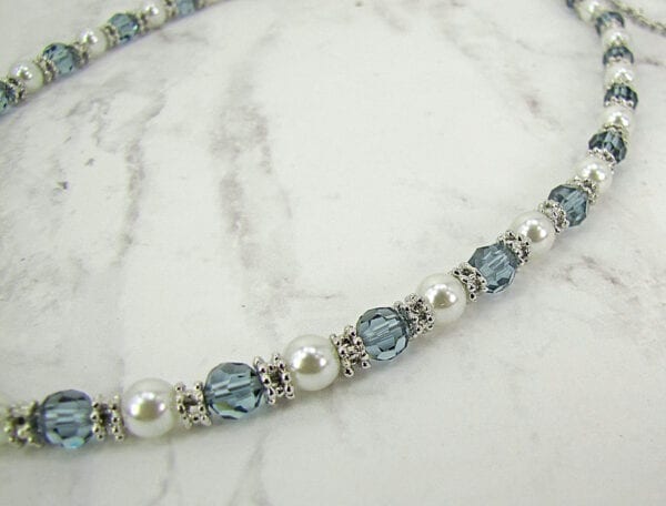 necklace with pearls and blue crystals on a marble surface