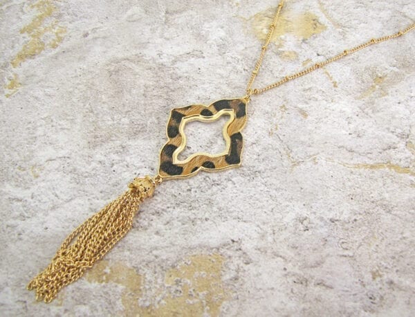 necklace with animal print pendant and brown tassel on a concrete surface