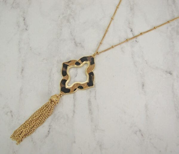 necklace with animal print pendant and brown tassel on a marble surface