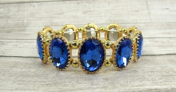 golden bracelet with sapphire gems on a wooden surface