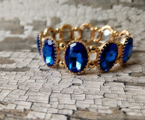golden bracelet with sapphire gems on a cracked leather surface