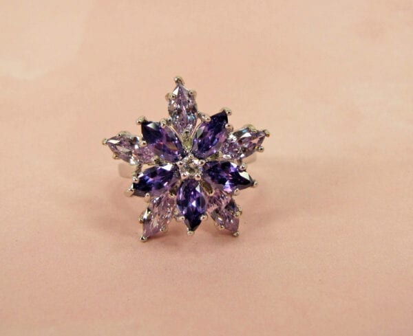 ring with violet gems arranged in a starburst on a pink surface