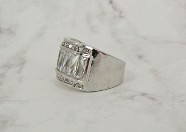 side view of a ring with rows of white rectangular crystals on marble surface