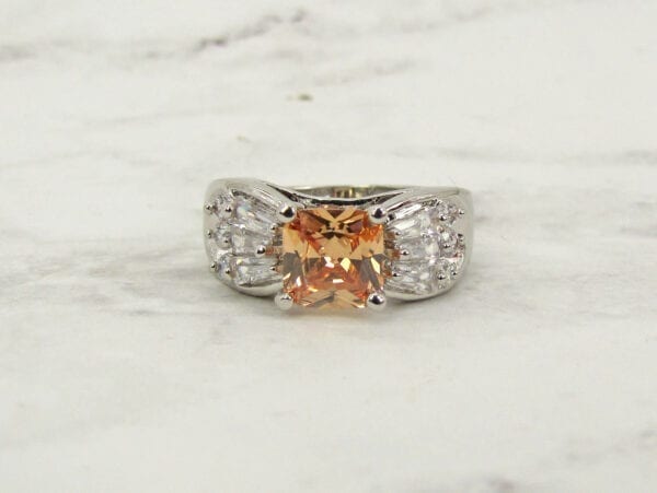 front view of a ring with orange gem on a marble surface