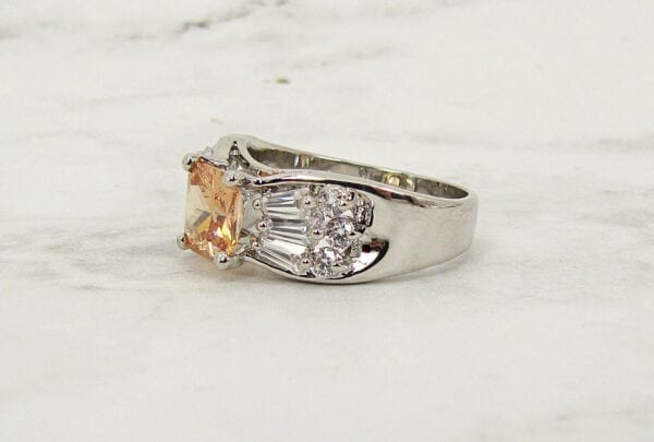 side view of a ring with orange gem on a marble surface
